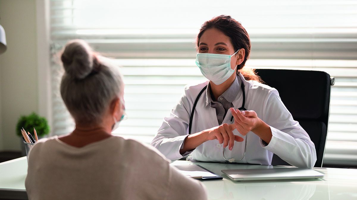 Female,Doctor,In,Medical,Facial,Mask,Have,Consultation,With,Elderly